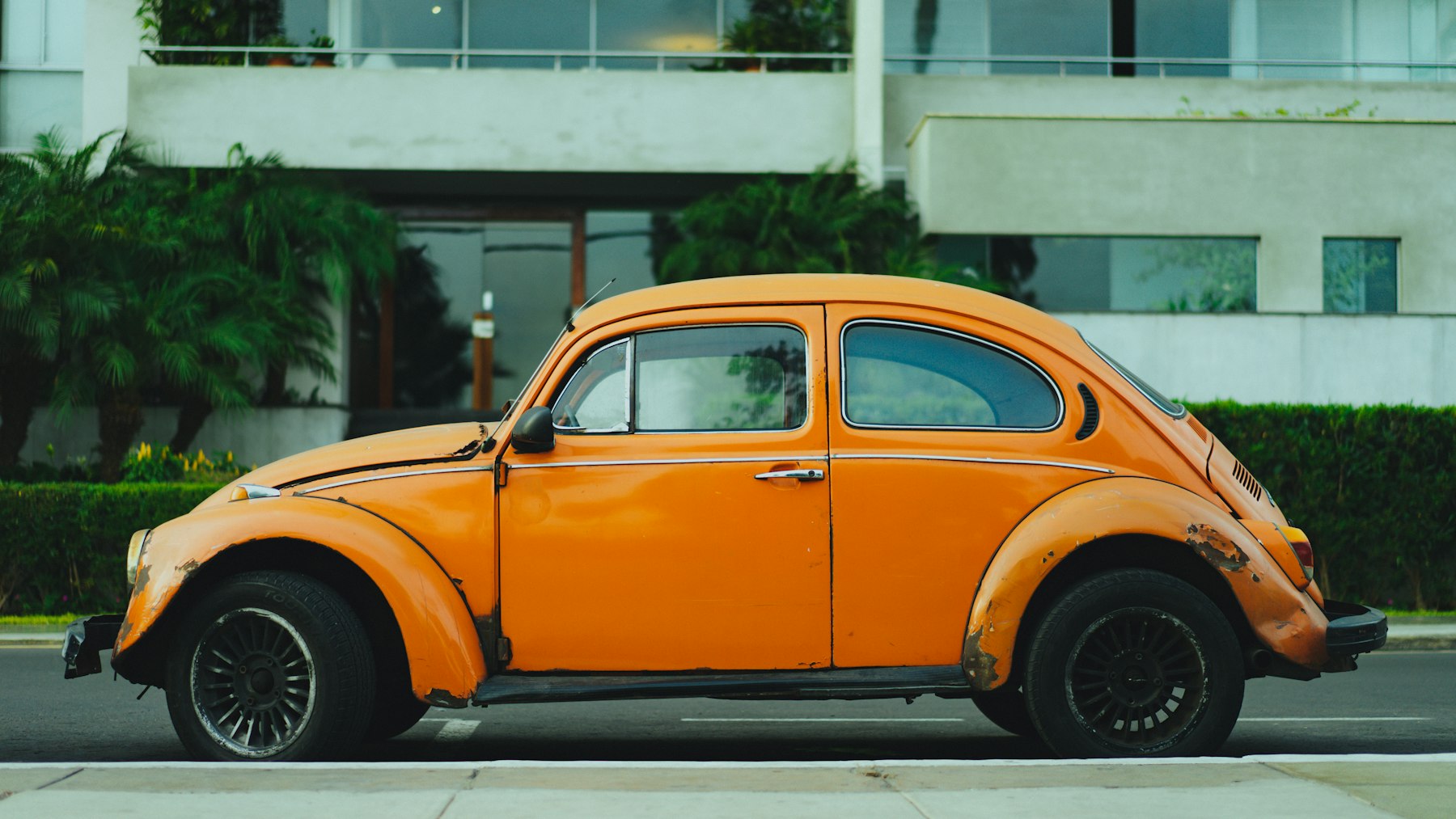 Orange classic Beetle parked outside a modern building