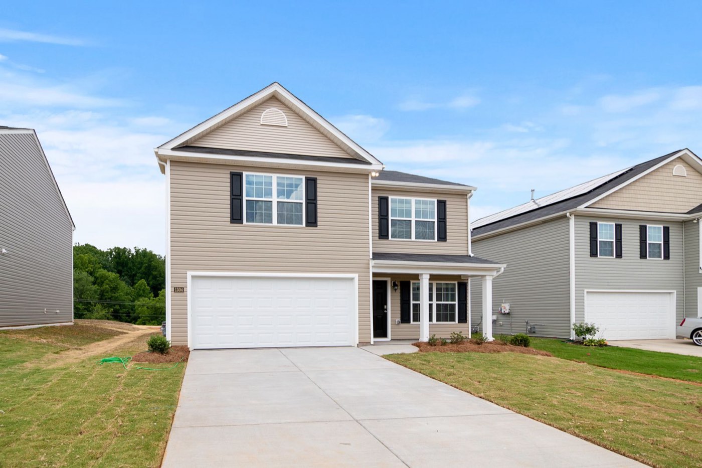 Two-story suburban house with vinyl siding, a covered porch and a wide concrete driveway