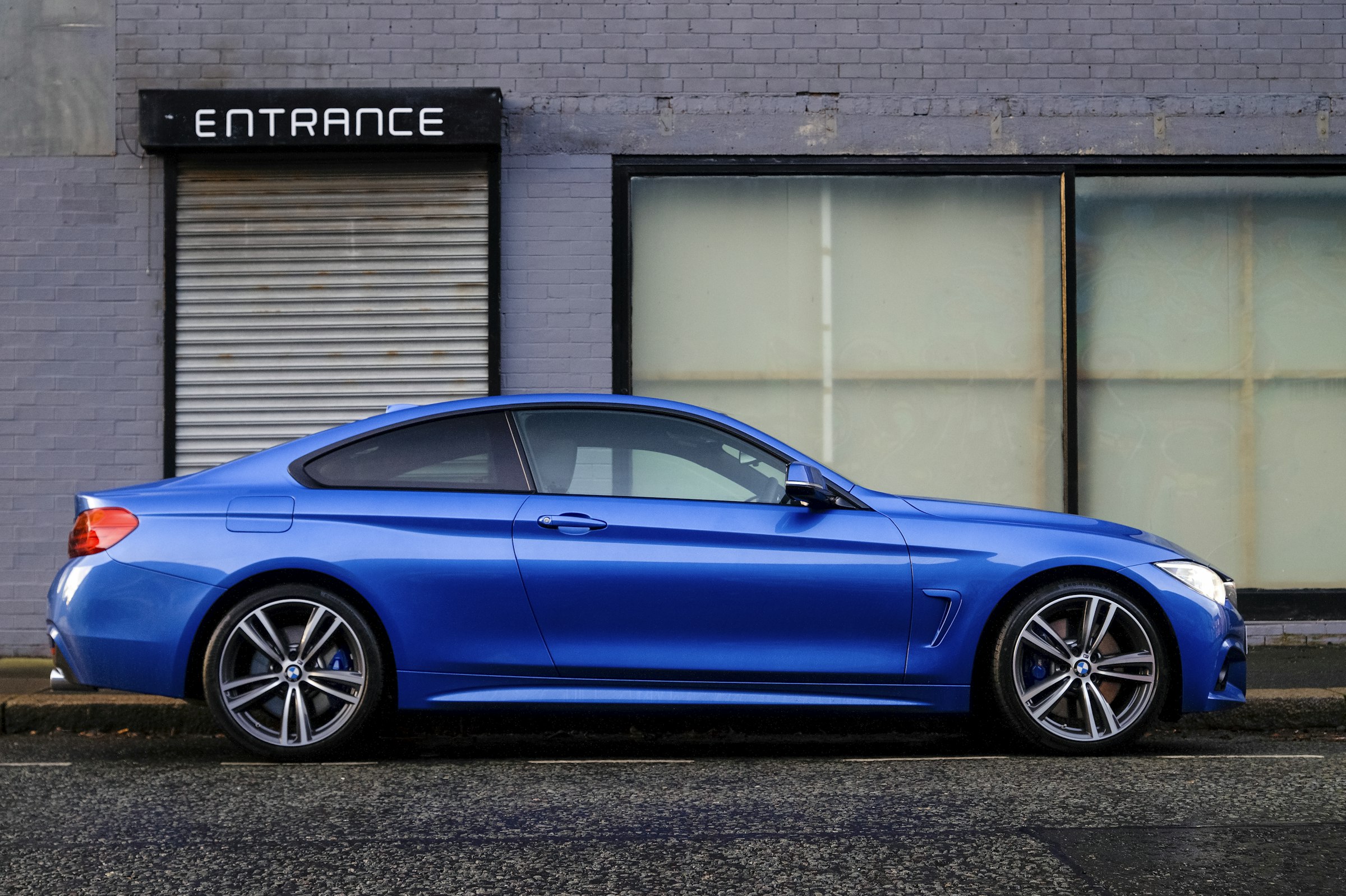 Blue coupe parked in front of a city entrance